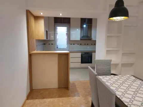 View from the dining area towards the open kitchen with a breakfast bar and built-in appliances. - image 7