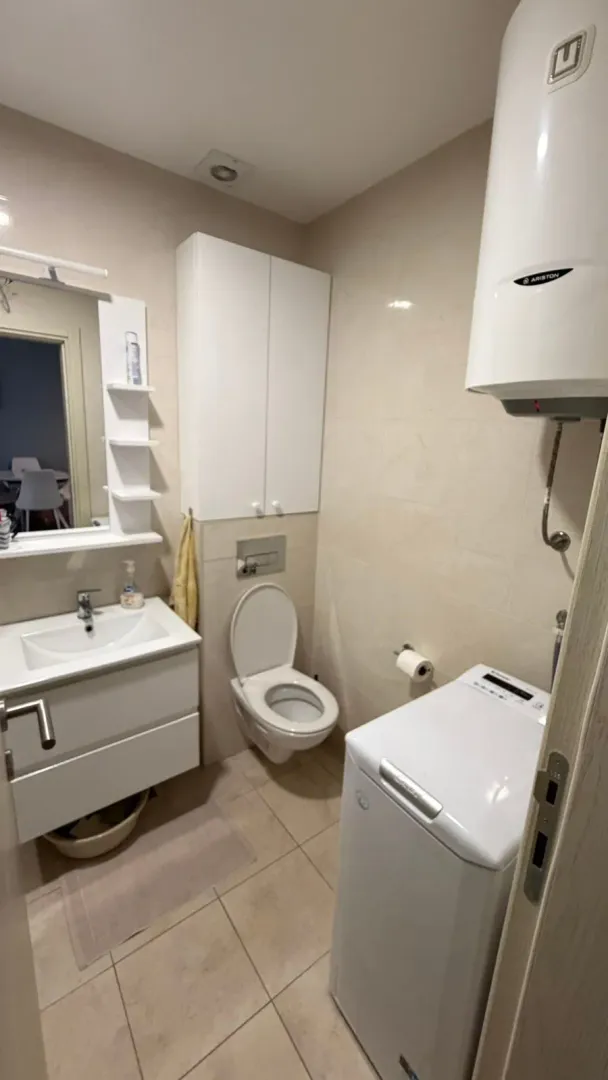 Compact bathroom with a sink, toilet, washing machine, and water heater.