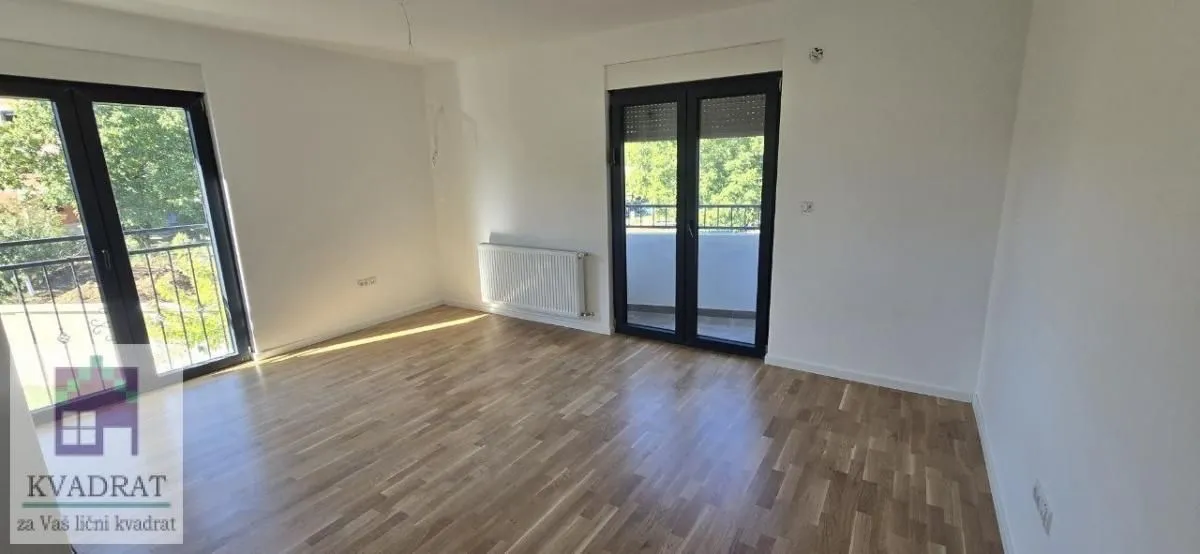 Prazna soba sa parketom i izlazom na terasu.