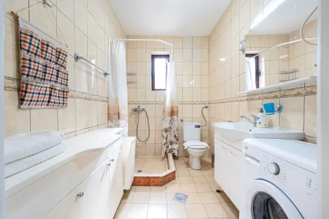 Bathroom equipped with a shower cabin, washbasin, and washing machine. - image 7