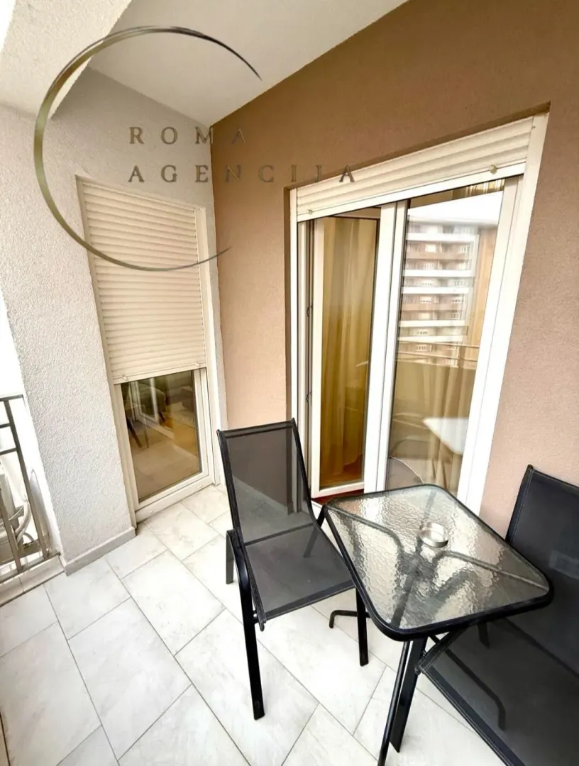 Manji namješten balkon sa stolom i dvije stolice.