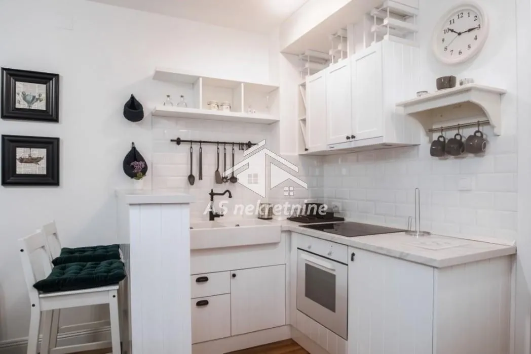 Small white kitchen with built-in appliances and a dining bar.