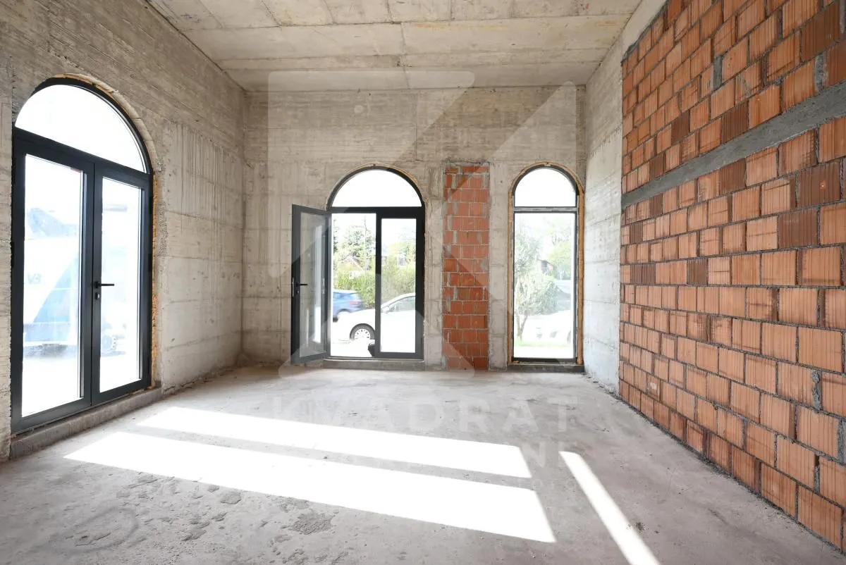 Unfinished room under construction with concrete and brick walls and window openings.