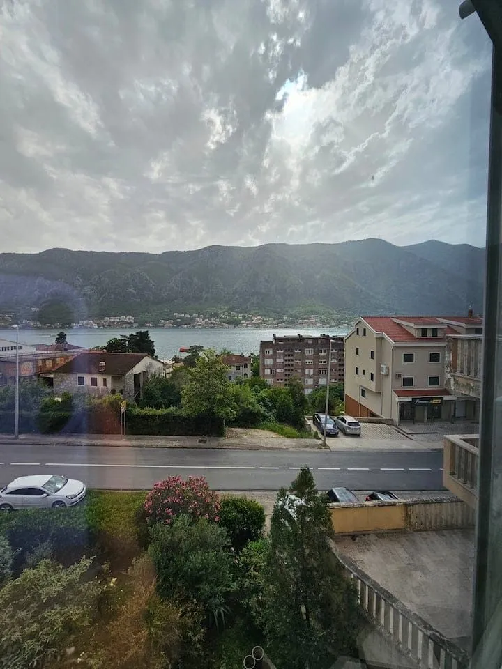 Pogled sa terase na more, okolne zgrade i planine.
