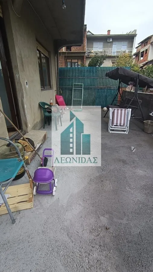 Concrete yard with garden furniture and children's toys in front of the house.