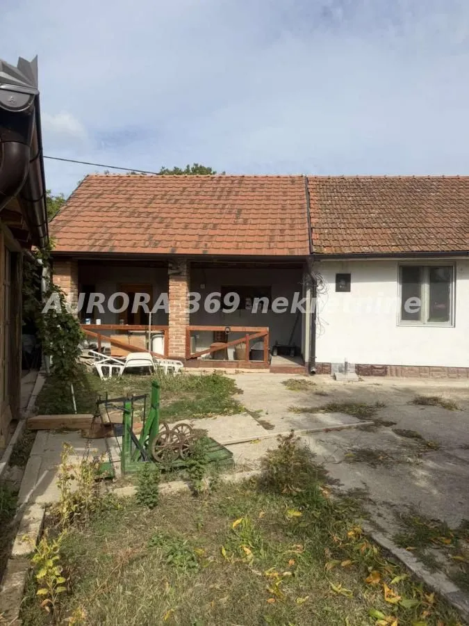 Pogled na dvorište i spoljašnjost prizemne kuće sa terasom.