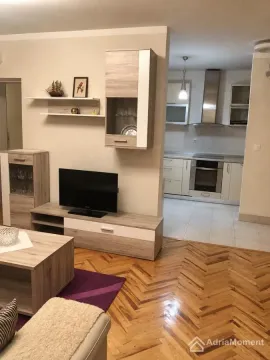Dnevna soba sa garniturom, televizorom i pogledom na kuhinju u pozadini. - image 4