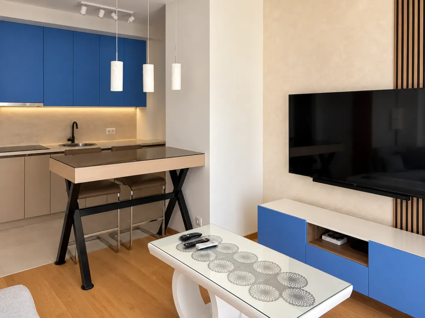 Living room with a dining table and a kitchen in the background.