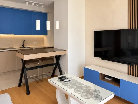 Living room with a dining table and a kitchen in the background. - image 8