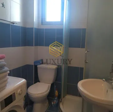 Small bathroom with blue and white tiles, toilet, sink, and shower cabin. - image 4