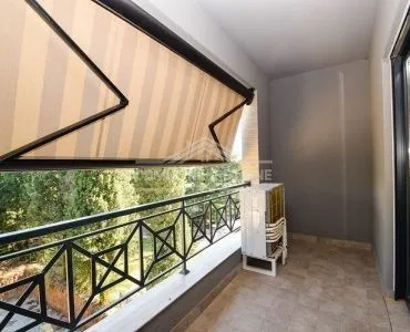 Uski balkon sa tendom i pogledom na zelenilo.