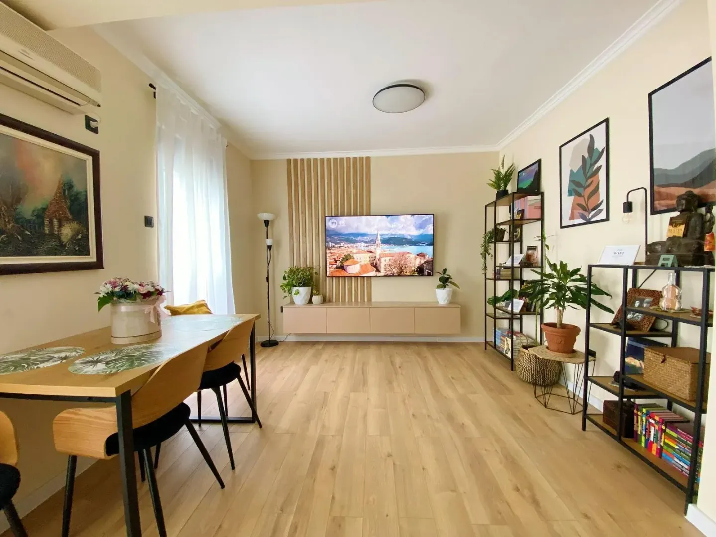 Living room with a dining area, wooden flooring, and a wall-mounted TV.
