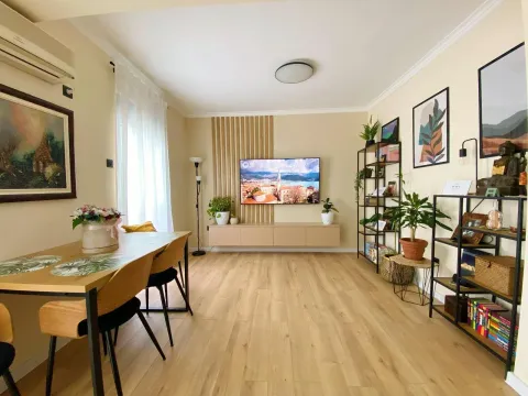 Living room with a dining area, wooden flooring, and a wall-mounted TV. - image 2