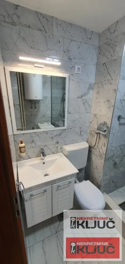Kupatilo obloženo mermernim pločicama sa umivaonikom, ogledalom i WC šoljom.