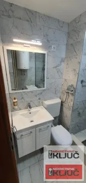 Kupatilo obloženo mermernim pločicama sa umivaonikom, ogledalom i WC šoljom. - image 14