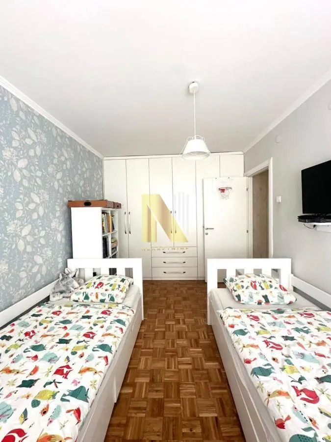 Dečja spavaća soba sa dva kreveta i belim ormanom.