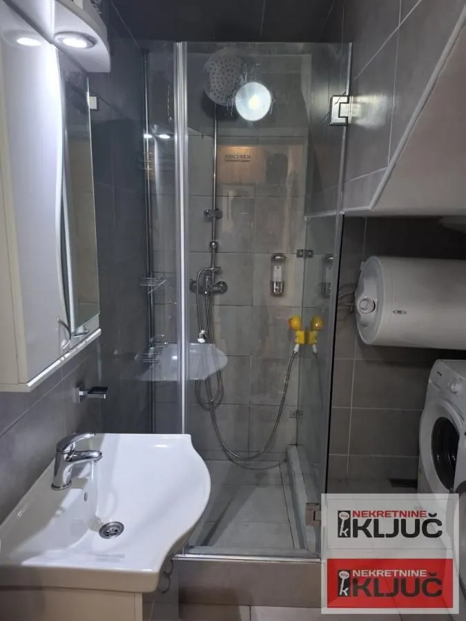 Kupatilo sa tuš kabinom, umivaonikom i veš mašinom.