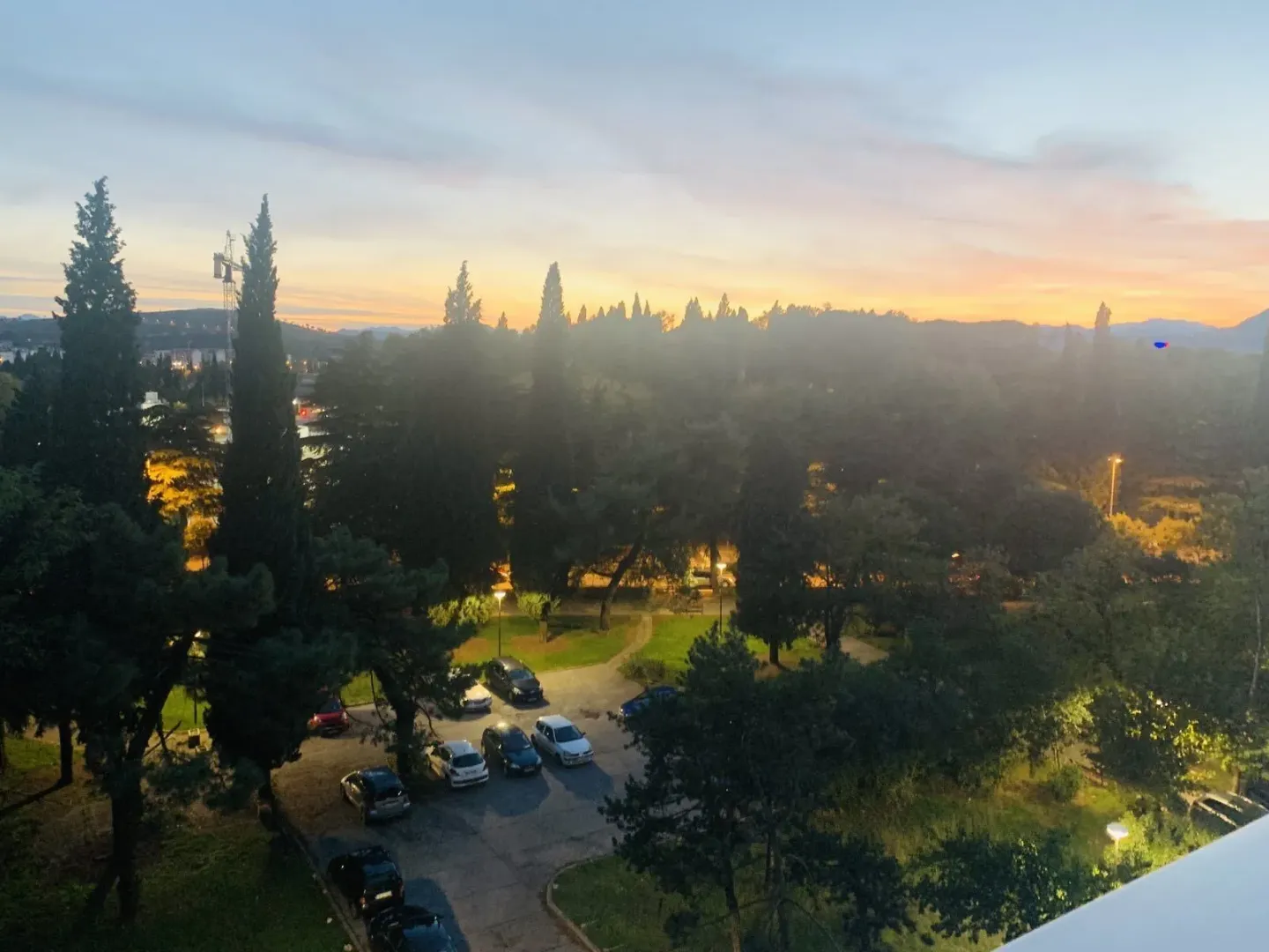View from the balcony overlooking a park and parking lot at sunset.