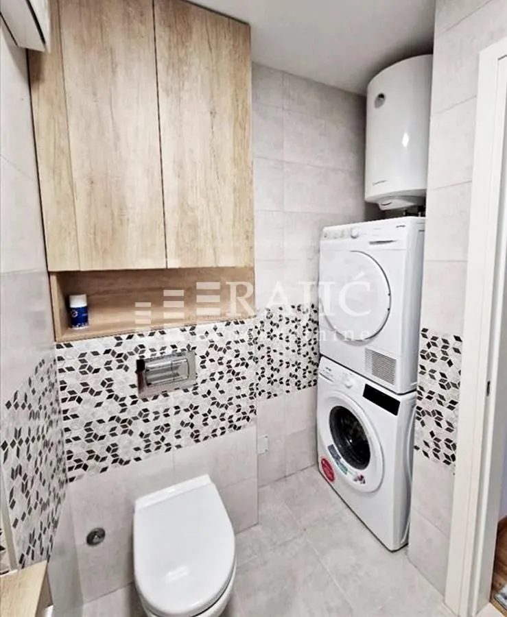 Small bathroom with built-in cabinet, toilet, and washing machine.