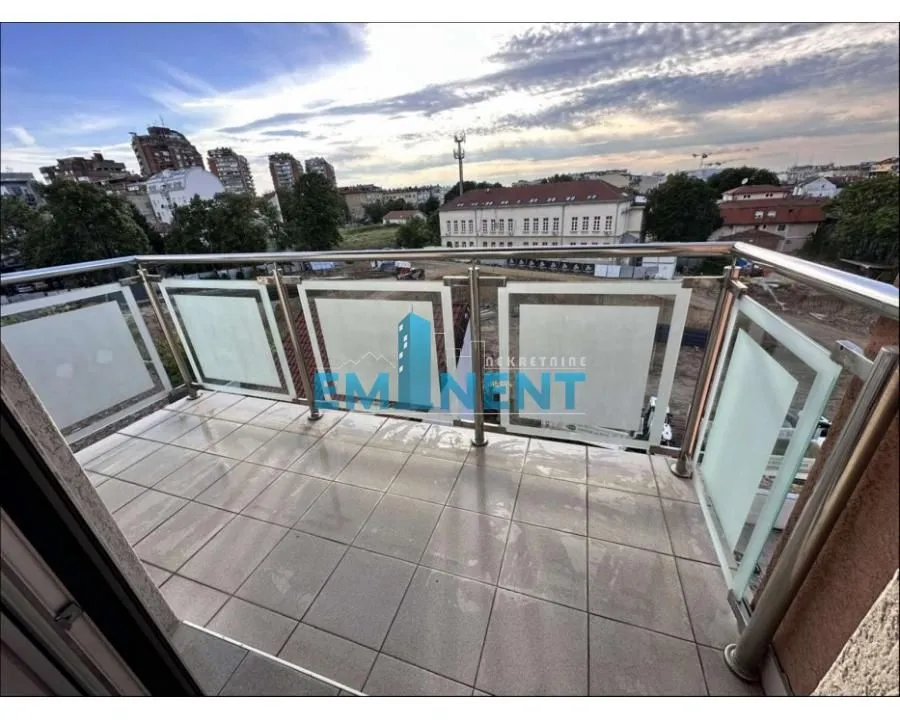 Popločani balkon sa metalnom ogradom i pogledom na grad.