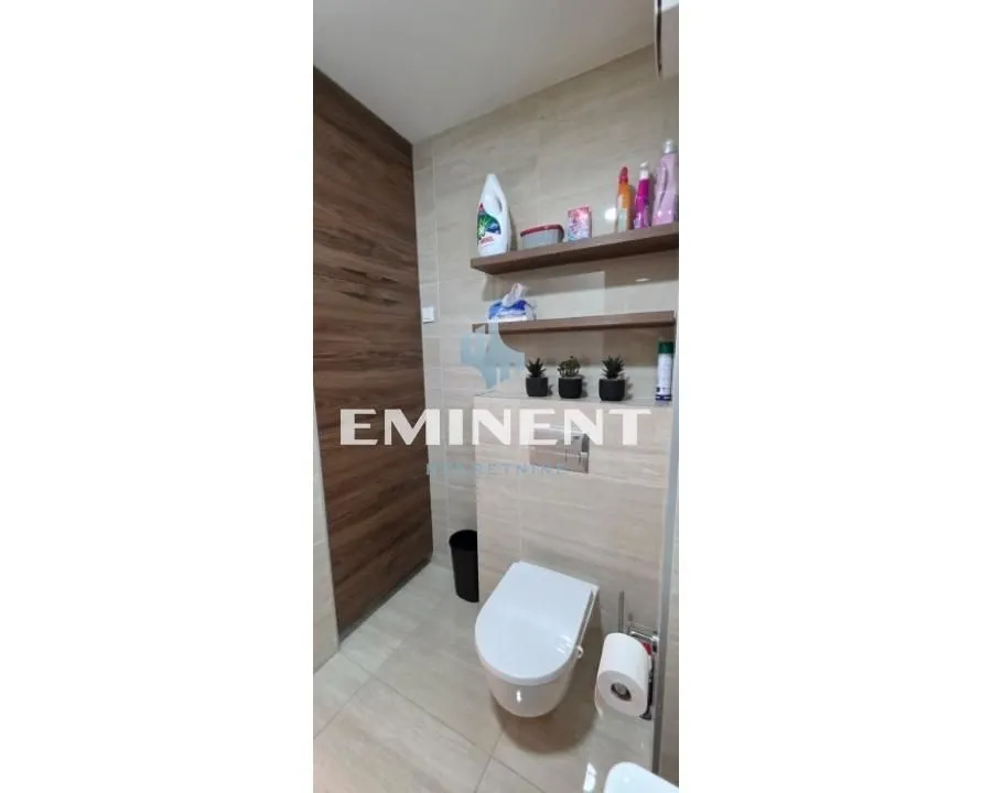 View of the bathroom with a wall-hung toilet and shelves.