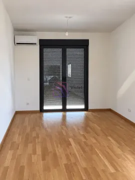 Prazna soba sa drvenim podom, klima uređajem i balkonskim vratima sa spuštenim roletnama. - image 5