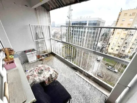 Natkriveni balkon sa metalnom ogradom i pogledom na grad. - image 2