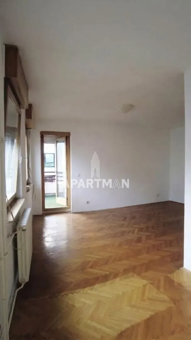 Empty room with hardwood parquet flooring and access to the terrace.