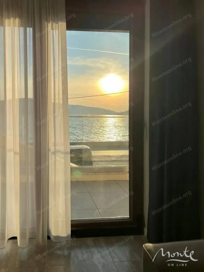 Pogled na more i zalazak sunca kroz balkonska vrata.