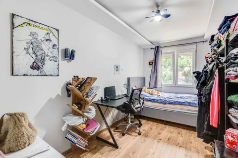 Furnished bedroom with a bed, desk, and shelving units. - image 8