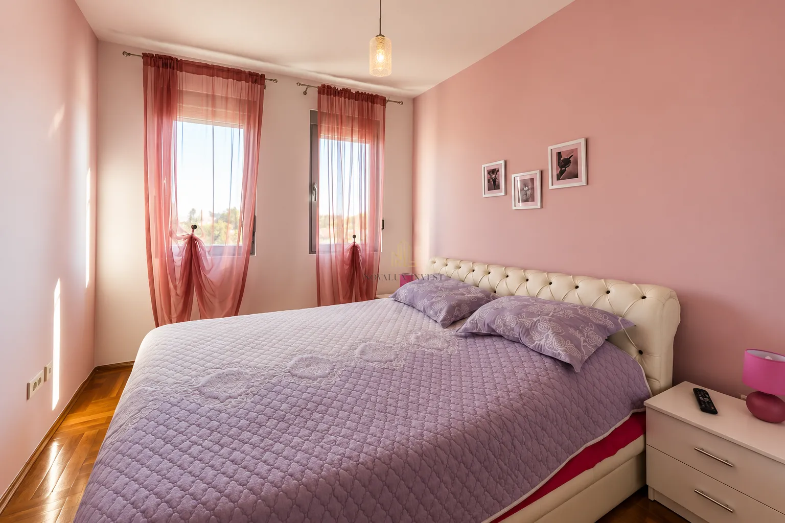 Spavaća soba sa bračnim krevetom i roze zidovima.
