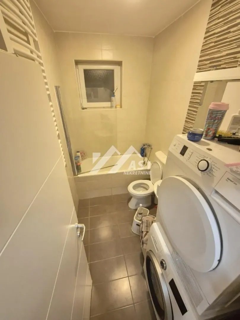 Manje kupatilo opremljeno sanitarijama, kadom i veš mašinom.