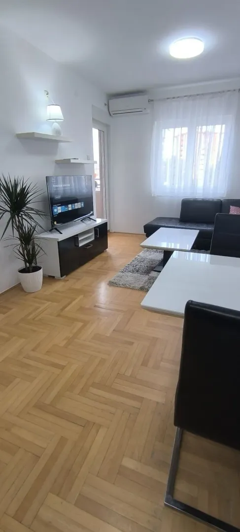 Bright living room featuring parquet flooring, a TV stand, and leather seating.