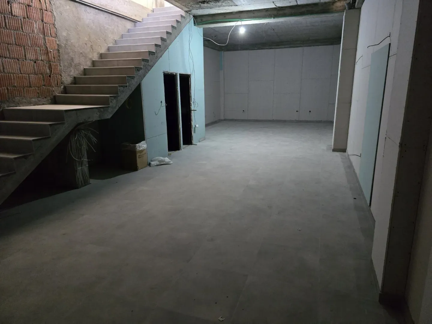 A spacious room in the gray phase of construction with an internal staircase.
