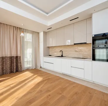 Modern kitchen with white cabinetry and wooden flooring. - image 9