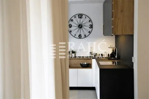 View from the hallway into a modern kitchen with a large wall clock. - image 4
