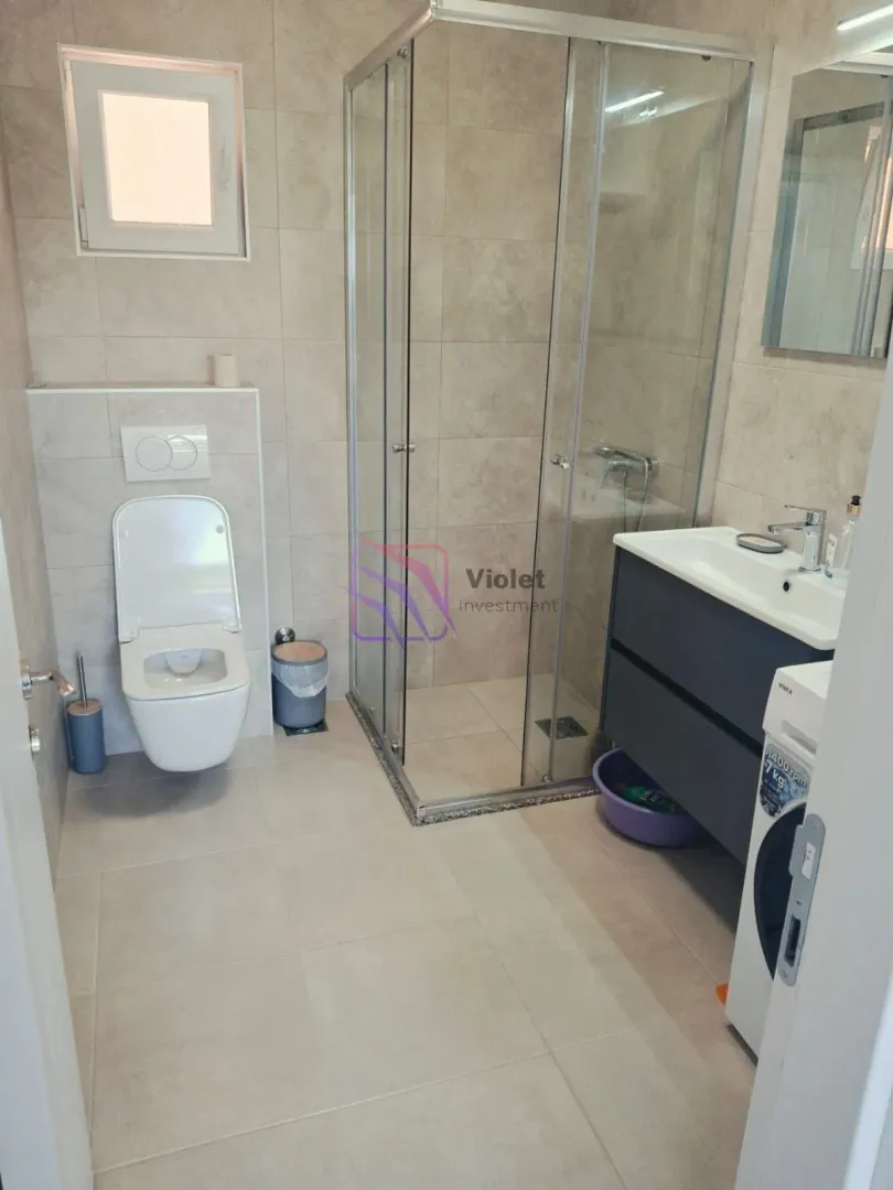 Moderne kupatilo sa tuš kabinom, umivaonikom i ugrađenom wc šoljom.