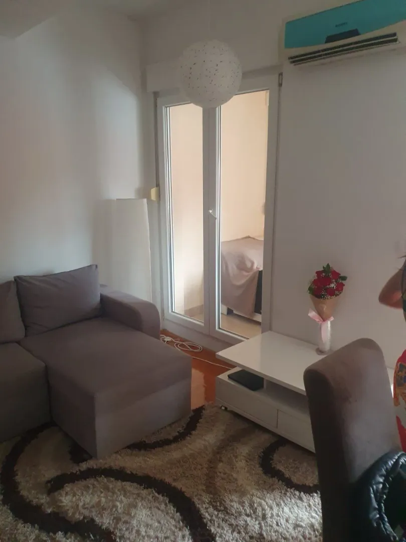 Living room with a corner sofa, carpet, and a view into the adjacent room.