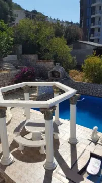 Yard with a swimming pool, covered seating area, and barbecue. - image 4