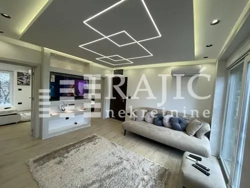 Modern living room with a sofa and a dropped ceiling with lighting.