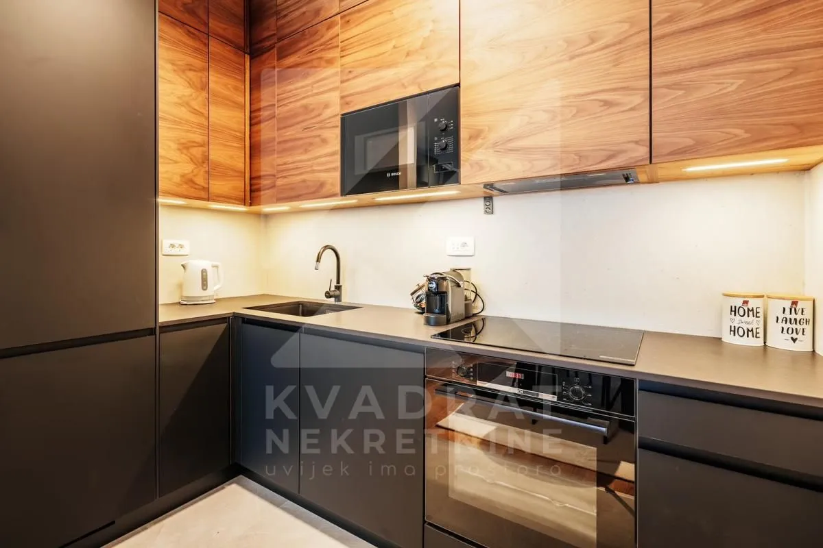Modern kitchen with dark cabinetry and wooden wall units.