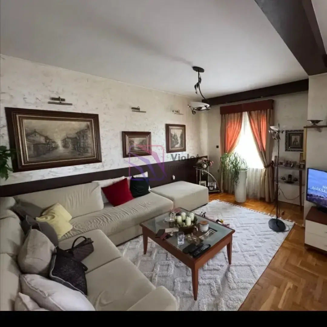 Dnevna soba sa garniturom, stočićem i televizorom.