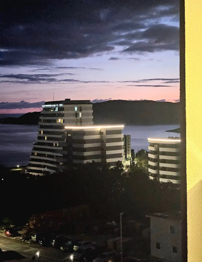 View from the terrace of buildings at dusk and the sea in the distance.