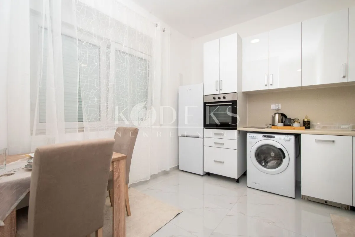 White kitchen with a dining table and built-in appliances.