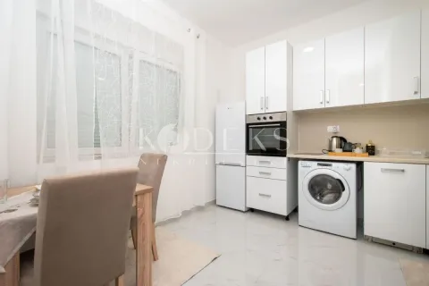 White kitchen with a dining table and built-in appliances. - image 3