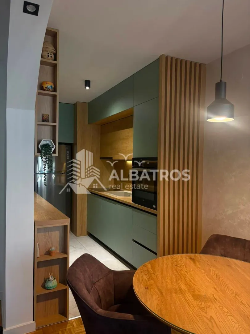 Modern kitchen with wooden elements and built-in appliances, connected to the dining area.