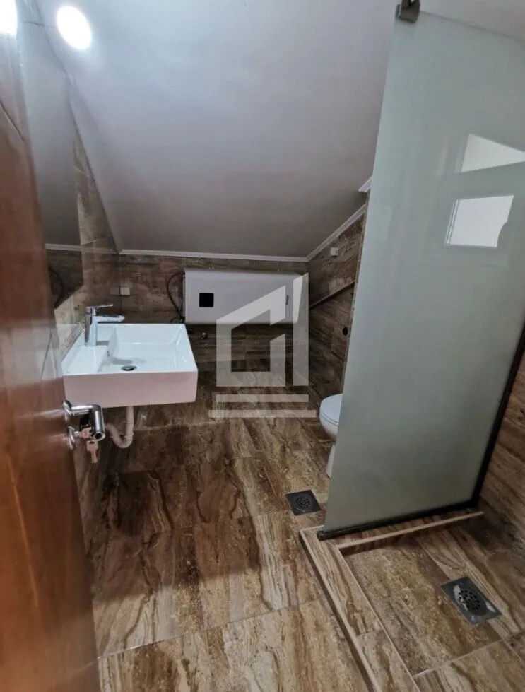 Kupatilo sa umivaonikom, tuš kabinom i wc šoljom pod kosim plafonom.