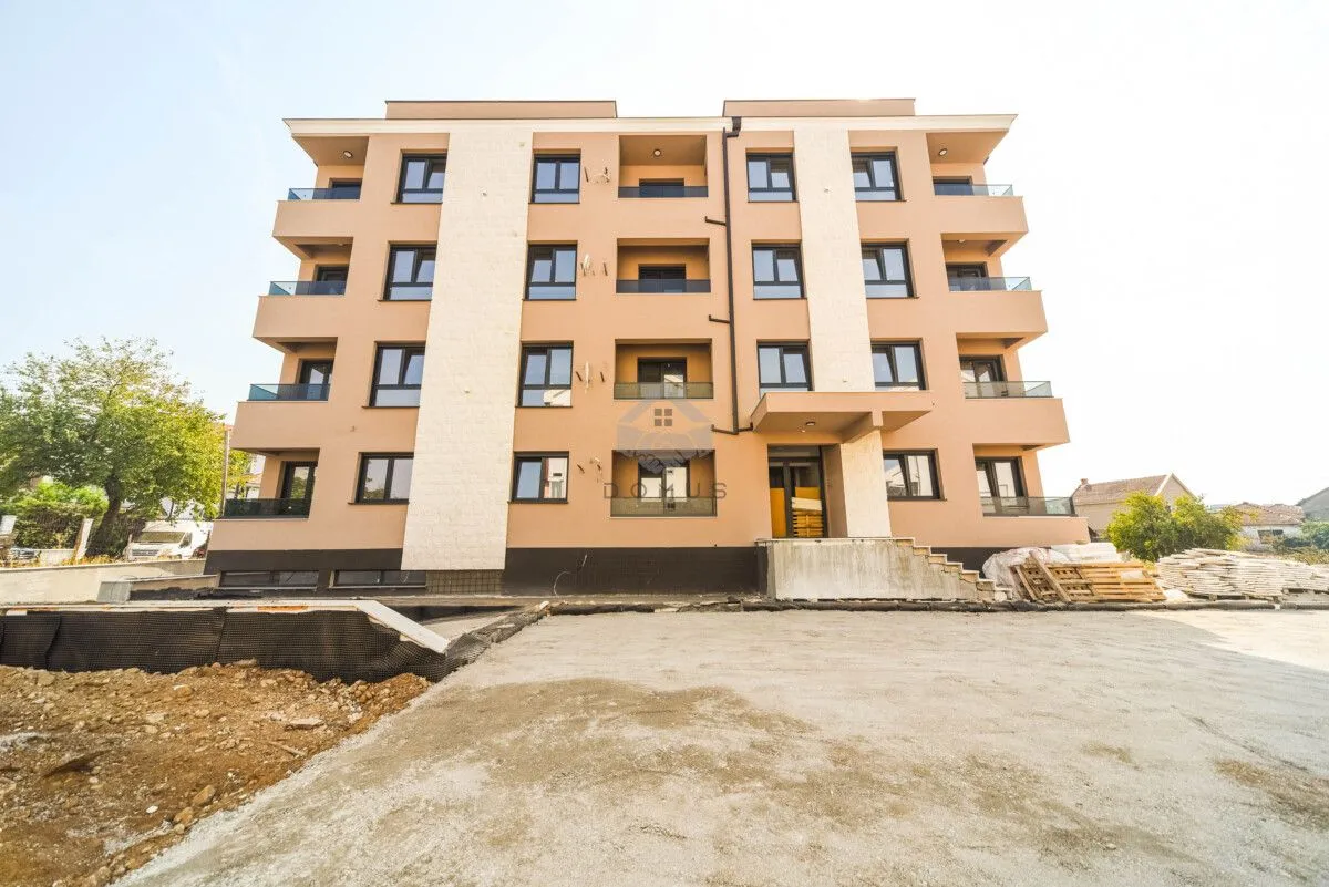 Prednji pogled na novu stambenu zgradu sa balkonima i uređenim dvorištem.