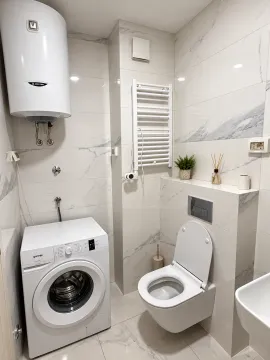Modern equipped bathroom with a toilet, washing machine, and water heater. - image 2