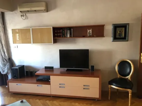 Living room with a TV stand, wall shelves, and an accent chair. - image 7